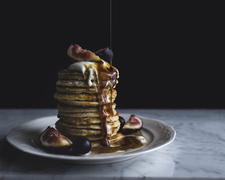 Chocolate syrup pouring on stack of pancake served on plate