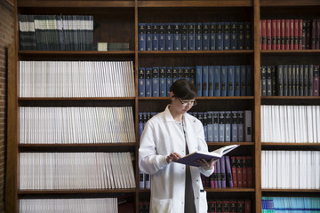 Female scientist reading book in library