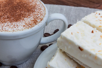 cup of cappuccino with cinnamon and white cakes