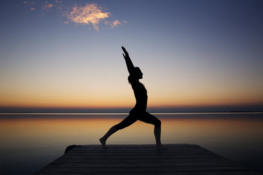 Woman at seaside doing yoga at sunset