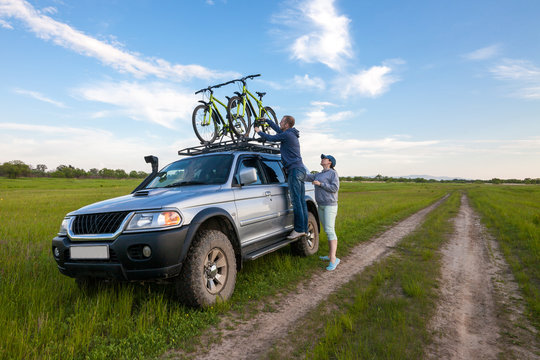 Young couple taking off their bicycles from roof rack