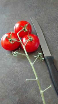 Strauchtomaten
Drei reife Strauchtomaten sind noch an einem Bl&uuml;tenstand. Daneben liegt ein Tomatenmesser. 
