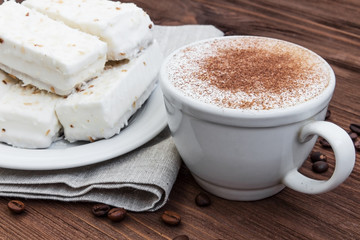 cup of cappuccino with cinnamon and white cakes