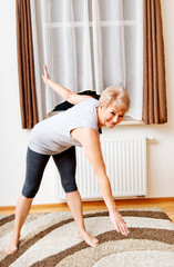 Senior woman doing yoga in living room