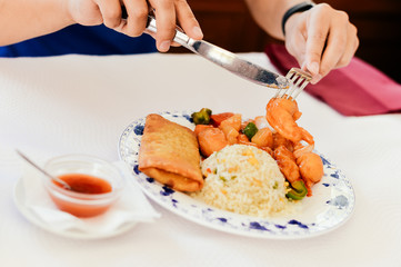 Person eating pan fried shrimps egg rice in white dish closeup table background