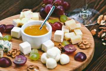 Cheese Board served with grapes and nuts on a wooden background