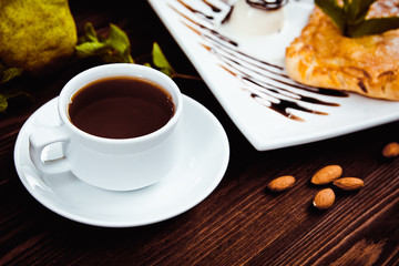 Hot chocolate along with a layer cake with pear and almonds decorated with chocolate and mint leaves