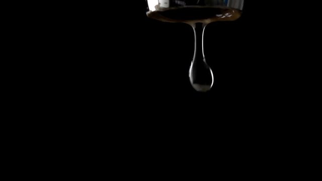 Macro slow motion video of dripping chrome water tap against dark background