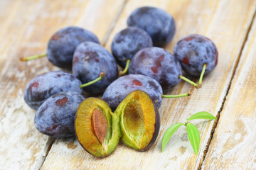 Fresh juicy plums spread out on rustic wooden surface
