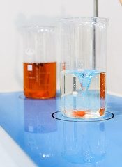 Glasses with chemical liquids are on a magnetic stirrer.