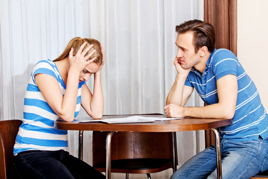 Worried couple calculating bills at home