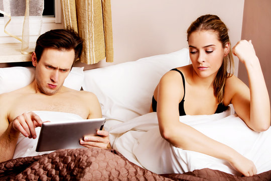 Couple In Bed-man Reading Woman Sitting Sad