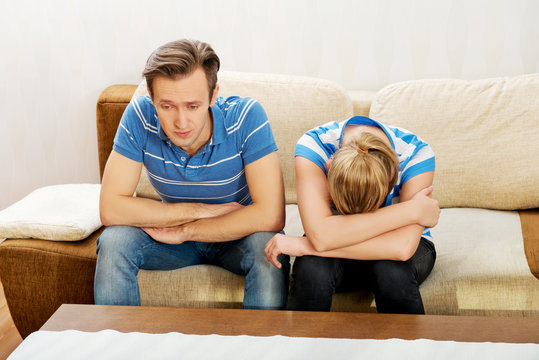 Worried couple after fight sitting on sofa