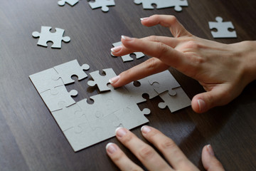 Female hands on a wooden office desk pick puzzle