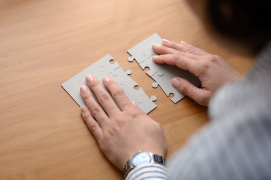 Female hands on a wooden office desk pick puzzle