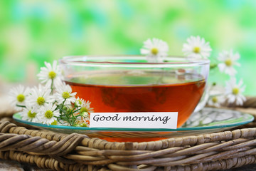 Good morning card with chamomile tea on green background with copy space
