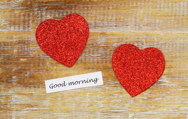 Good morning card with two sparkling hearts on rustic wooden surface
