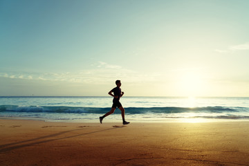 Man running on tropical beach at sunset