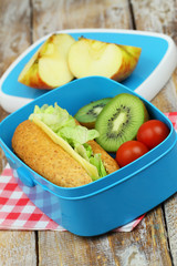 Healthy lunch box containing whole grain cheese sandwich, cherry tomatoes and kiwi fruit, closeup
