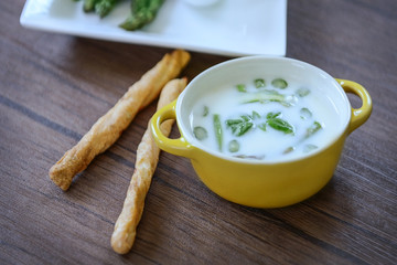 Asparagus soup with bread sticks on wooden table