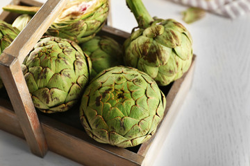 Obraz premium Artichokes in wooden container on light background
