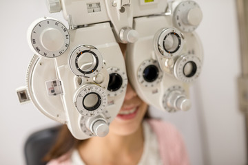 Woman looking through phoropter during eye exam