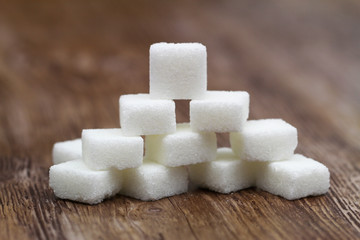 Stack of white sugar cubes on wooden surface
