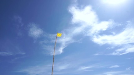 Yellow safety beach warning flag of ocean hazards and surf conditions with beautiful cloud blue sky