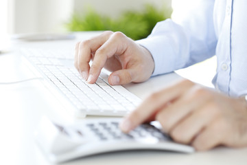 Calculating expenses. Close-up of investment advisor calculating expenses while sitting at office in front of computer