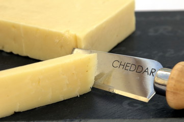 Fresh cut cheddar cheese on a slate board