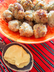 fried meatballs on a plate with a wooden spoon with mustard 