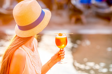 Young woman with glass of Spritz Aperol sitting near the water chanal in Venice on the sunset....