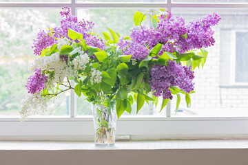 Lilac bouquet in vase on window