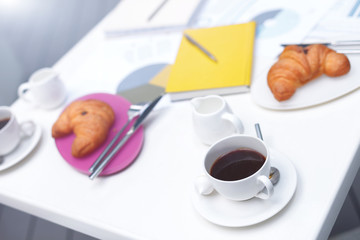 Hot beverage with food and documents on table
