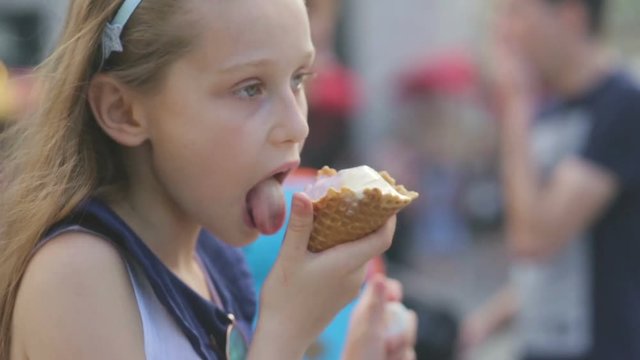 Little girl eating Ice Cream on a Hot, Torrid Summer Day at Playground in Park, Children