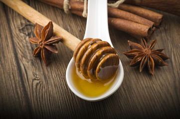 wooden honey dipper and spices on wood table
