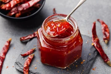 Gordijnen Tomato and chili sauce, jam, confiture in a glass jar on a grey stone background © annapustynnikova