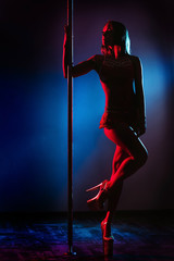 Beautiful woman performing pole dance. Studio shot, on colored background. silhouette