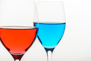 two glasses with blue colored water and wine