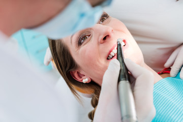Zahnarzt behandelt Zähne von Frau mit Bohrer