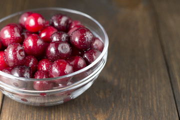 Sweet cherries in glass bowl on wooden background.