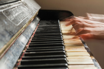Old rusty piano, selective focus, woman's hands on keyboard, intentionally blurred motion