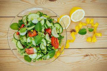 Diet plan, menu or program, tape measure and diet food of fresh vegetable salad, lemon on wood background, weight loss and detox concept, top view