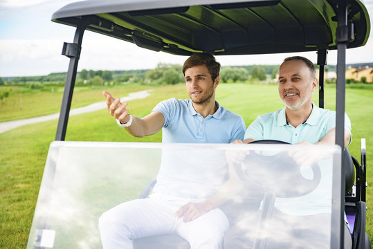 Two Men Driving Cart On Golf Course