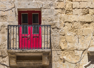 Fototapeta na wymiar Red door and a balcony, Valletta, island Malta