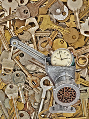 Alarm clock in meat grinder on old metal keys background.