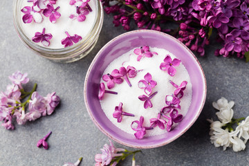 Lilac flowers sugar and syrup, essential oil with flower blossoms in glass jar Grey stone background Top view