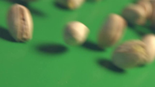Pistachios on a green background. 2 Shots. Slow motion. Horizontal pan. Close-up.