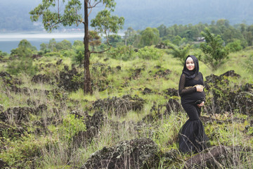 Naklejka premium asian pregnant woman wearing hijab with nature landscape
