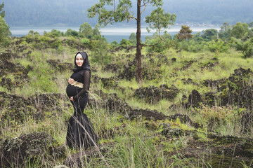 asian pregnant woman wearing hijab with nature landscape